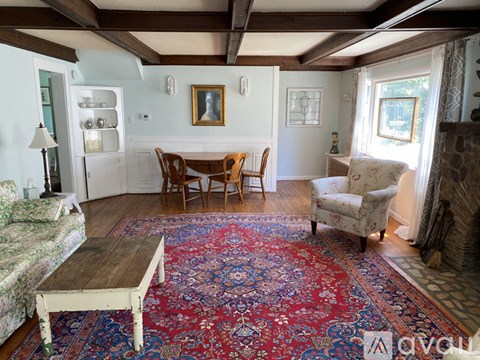 A living room with a rug on the floor and a fireplace on the right.