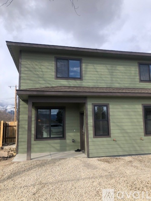 A house with a green siding and a brown roof.