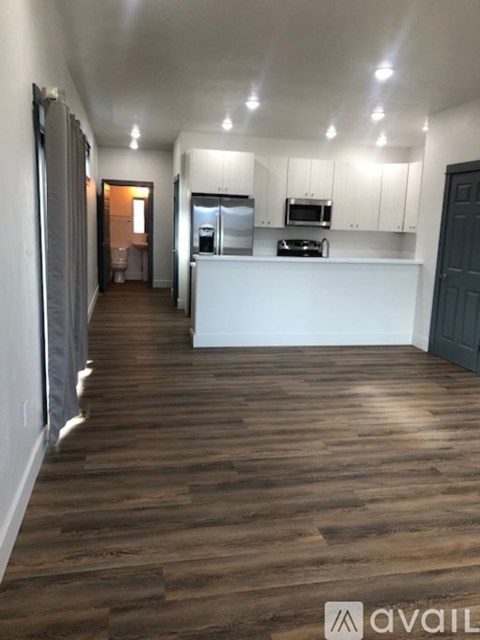A kitchen with white cabinets and a wooden floor.