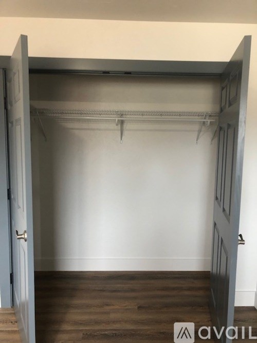 A room with a wooden floor and a white wall with a door open.