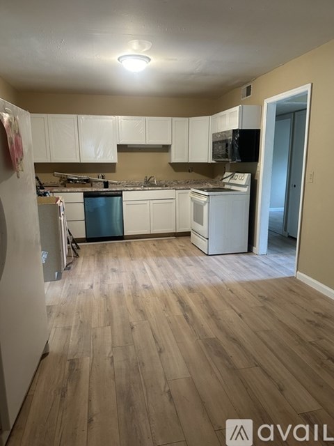 A kitchen with wooden floors and white cabinets.