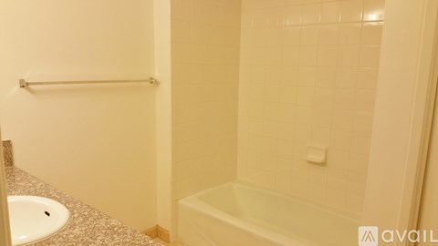 A bathroom with a tub, sink and a towel rack.