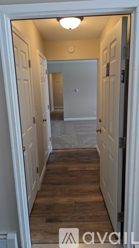 A room with a striped carpet and a door on the right side.