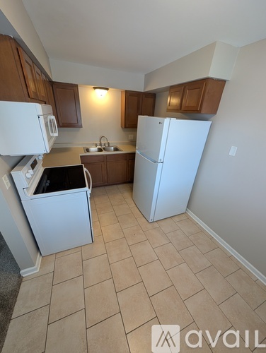 A kitchen with white appliances and brown cabinets.