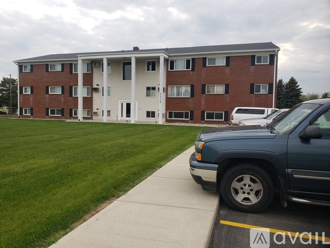 A blue truck is parked in front of a brick apartment building.