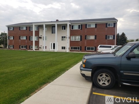 A blue truck is parked in front of a brick apartment building.