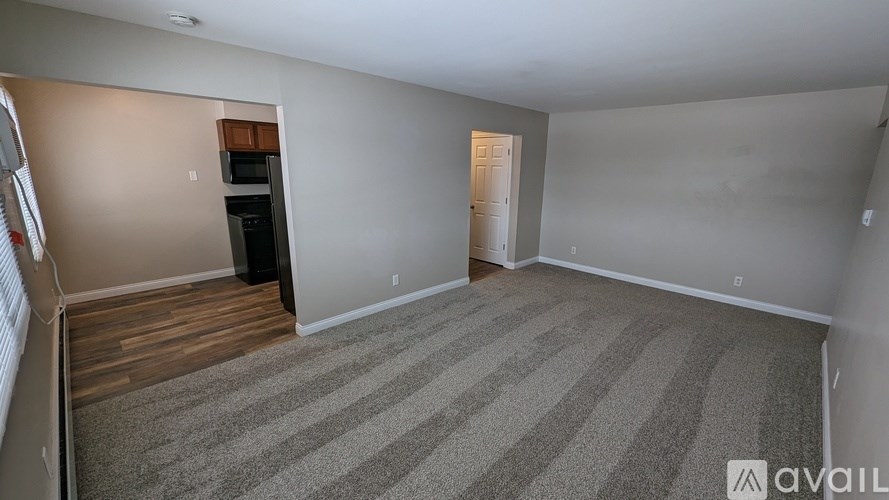 A room with a striped carpet and a door on the right side.
