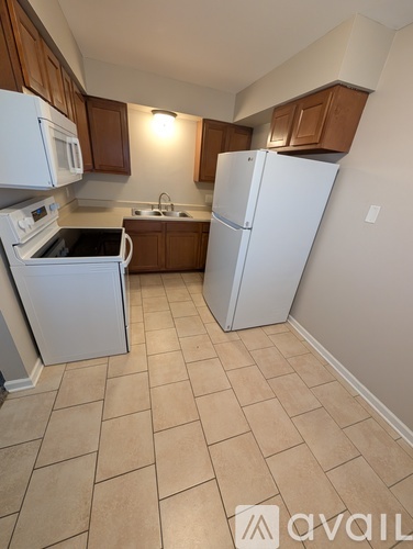 A kitchen with white appliances and brown cabinets.