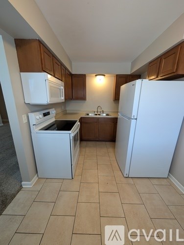 A kitchen with white appliances and brown cabinets.