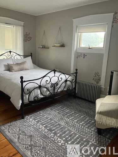 A bedroom with a black metal bed frame and a patterned rug.