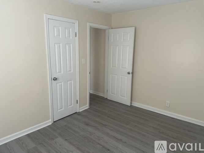 Two white doors in a room with wooden flooring.
