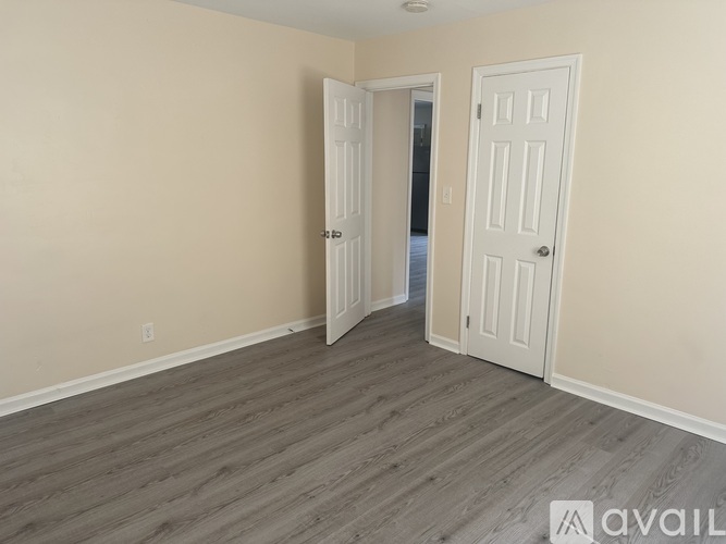 A room with two white doors and wooden flooring.