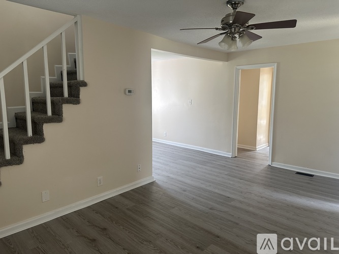 A spacious room with a staircase and a ceiling fan.