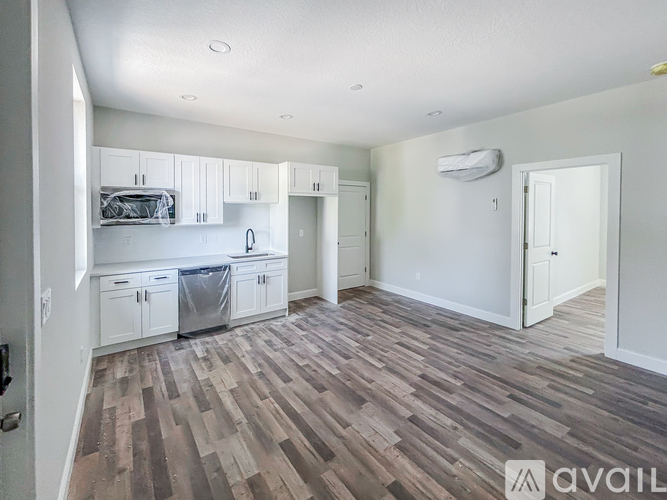 A spacious kitchen with white cabinets and a wooden floor.