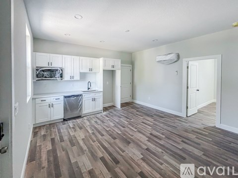 A spacious kitchen with white cabinets and a wooden floor.