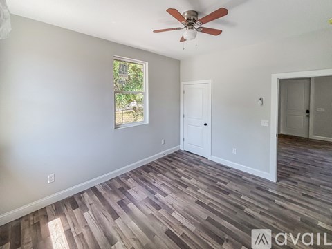 A room with a ceiling fan and wooden flooring.
