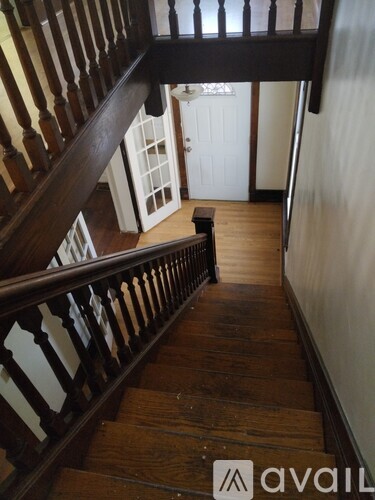 A wooden staircase with a balustrade and a door in the background.