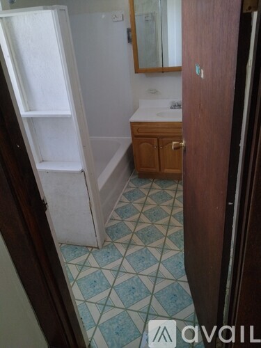 A bathroom with a white fridge and a wooden cabinet.