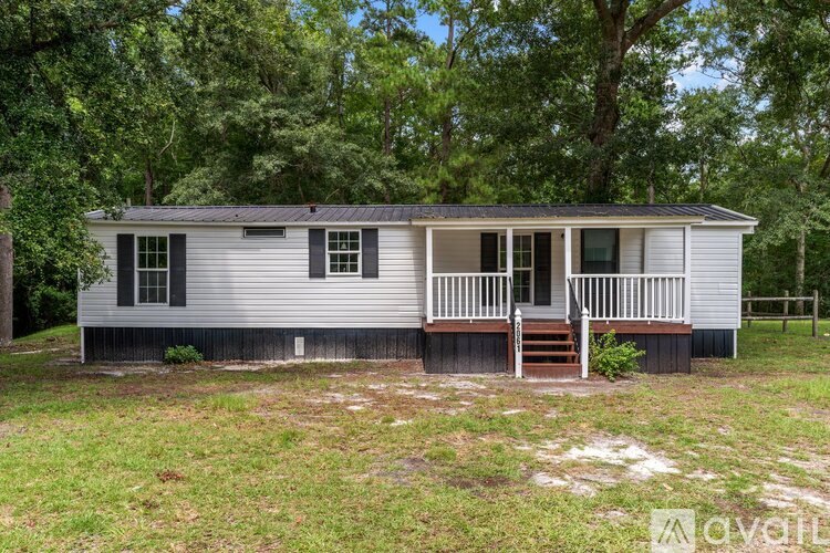 A mobile home with a porch and a small front yard.