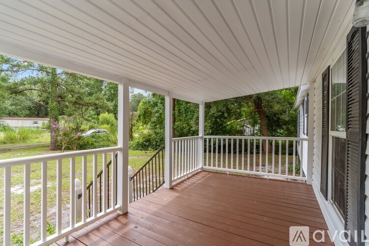 A white porch with a wooden floor and railings.