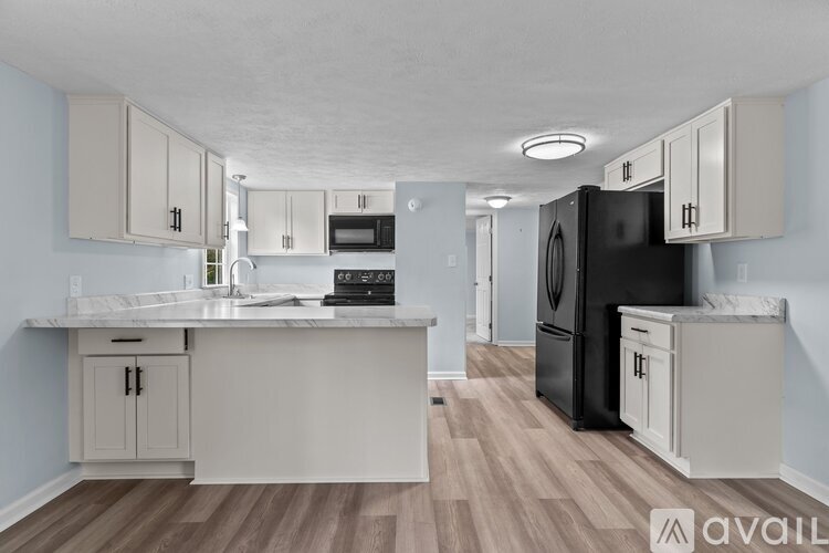 A kitchen with a black refrigerator and white cabinets.