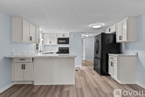 A kitchen with a black refrigerator and white cabinets.