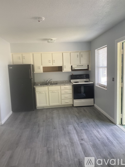 A kitchen with white cabinets and a black refrigerator.