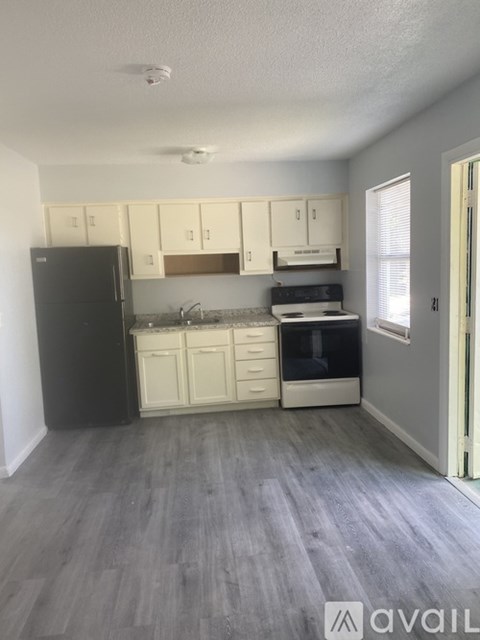 A kitchen with white cabinets and a black refrigerator.