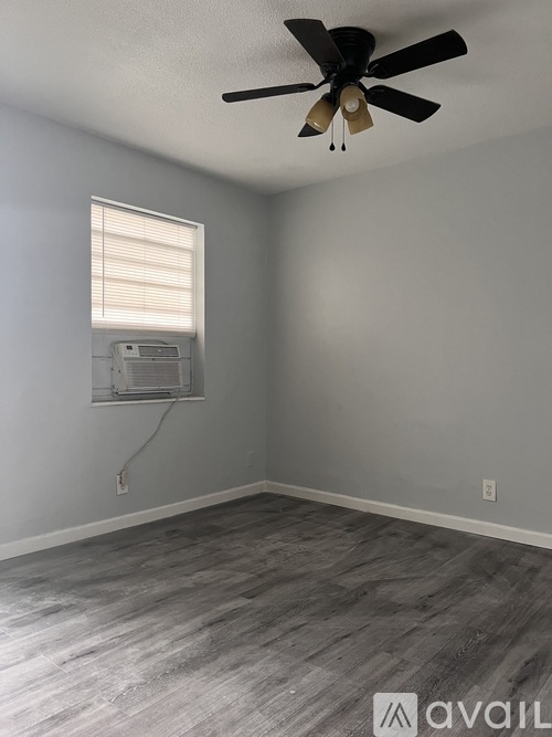 A room with a ceiling fan and a window with blinds.