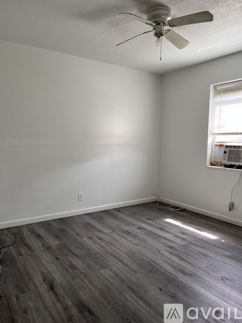 A room with a ceiling fan and wooden flooring.