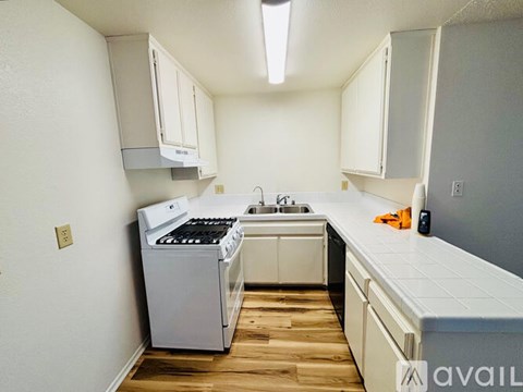 A kitchen with white cabinets and a white stove top oven.