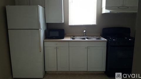 A kitchen with a white refrigerator, black oven, and a window letting in natural light.