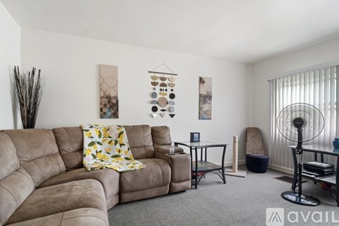 A living room with a brown sofa and a grey carpet.