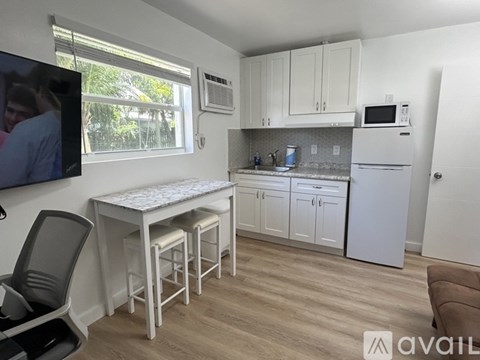 A kitchen with white cabinets and a table with four chairs.