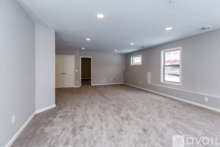 A spacious room with carpeted floor and a window on the right side.