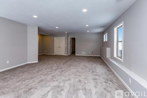 A spacious room with carpeted floor and a window on the right side.