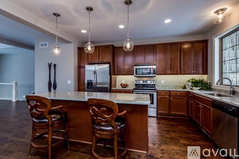 A kitchen with wooden cabinets and a center island with chairs.