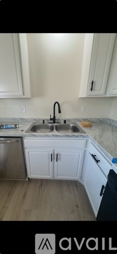 A kitchen with white cabinets and a stainless steel sink.