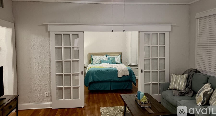 A bedroom with a bed, a couch, and a window with blinds.