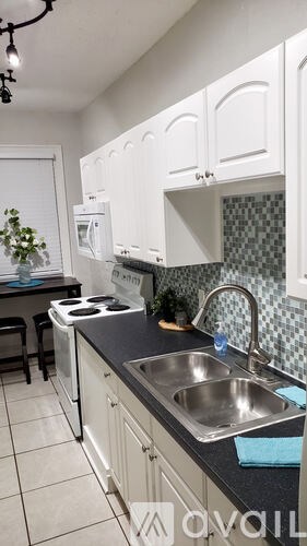 A kitchen with white cabinets and a black countertop.