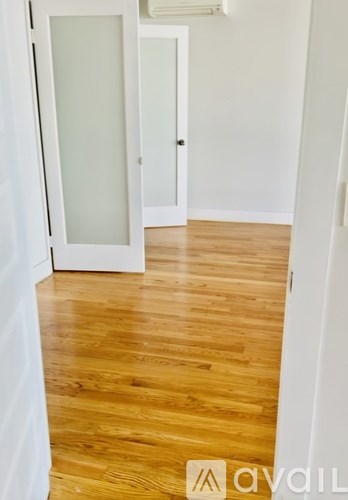 A hallway with a wooden floor and white walls.