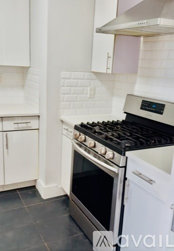 A modern kitchen with a stove top oven and white cabinets.