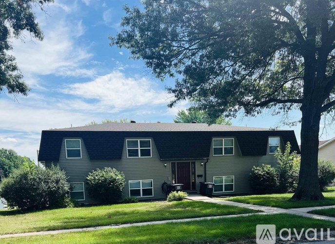 A house with a grey roof and a tree in front.