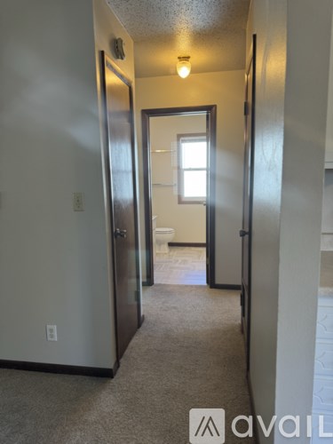 A hallway with a carpeted floor and a door on the right.
