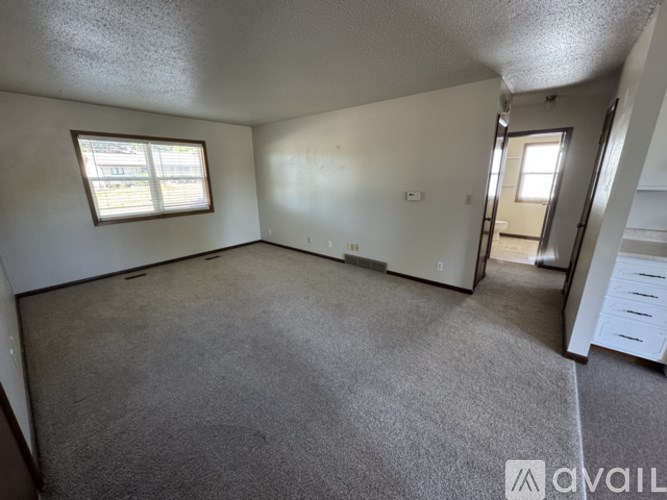 A spacious room with a window and a door leading to another room.