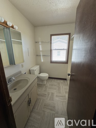 A bathroom with a toilet, sink, and mirror.