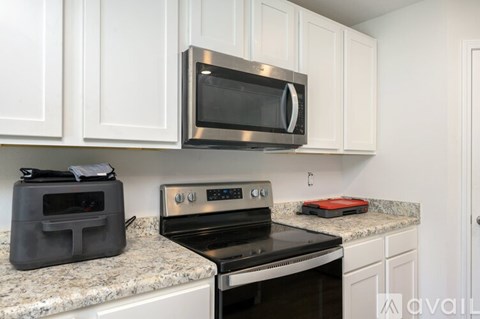 A kitchen with a black microwave above a stove.