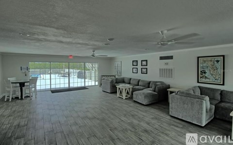 A spacious living room with a grey sofa set and a dining table.