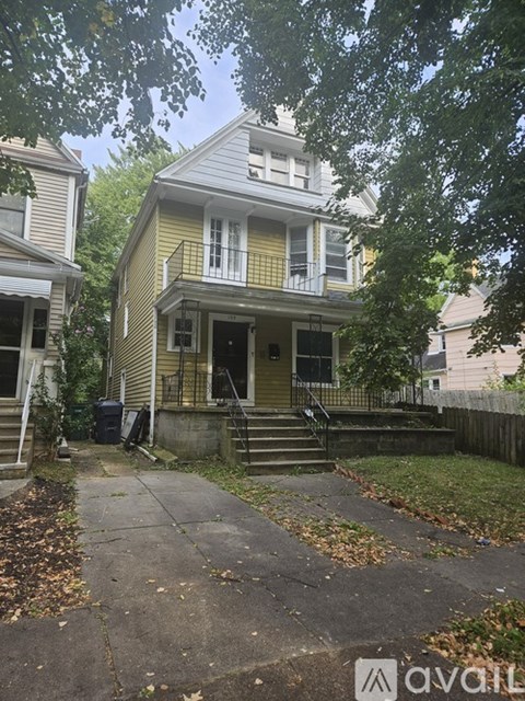 A house with a yellow front and a black trash can.