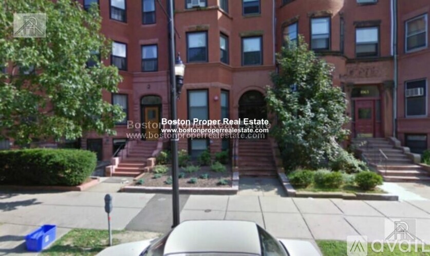 A street view of a residential area with apartment buildings and parked cars.